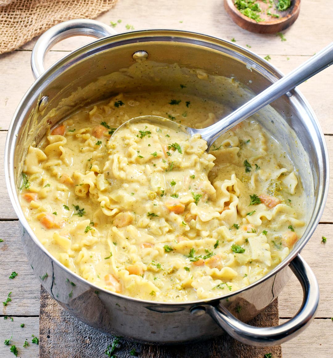 creamy vegan vegetable soup with gluten free noodles, beans and cashews in a large pot