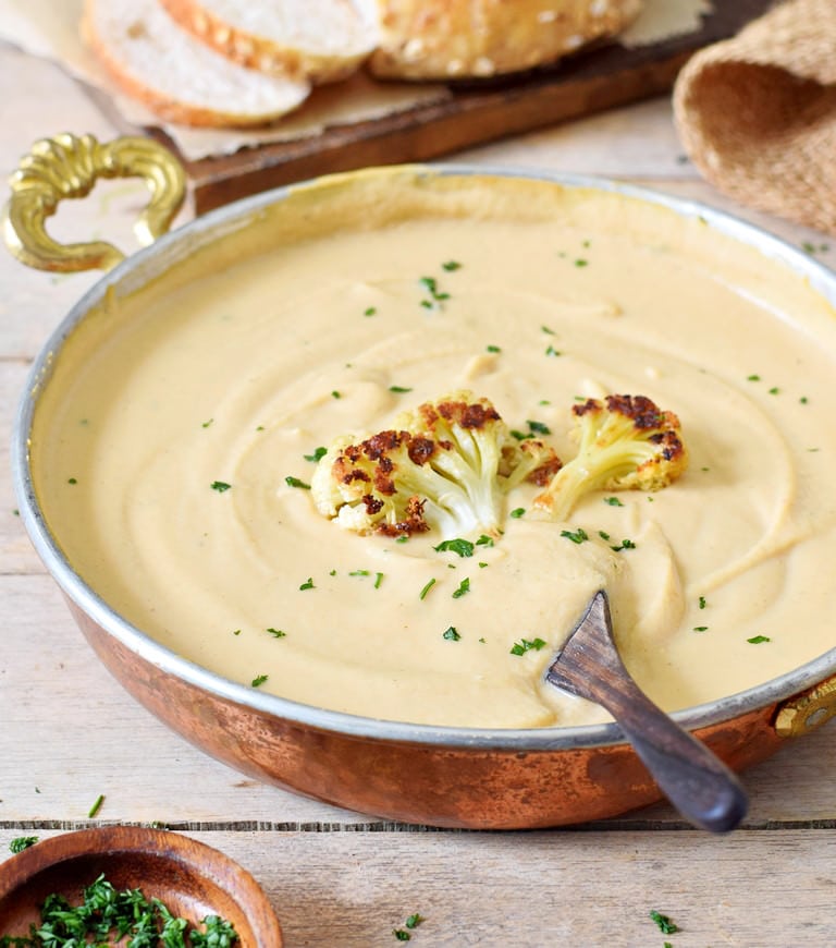 creamy vegan roasted cauliflower soup in bowl with spoon