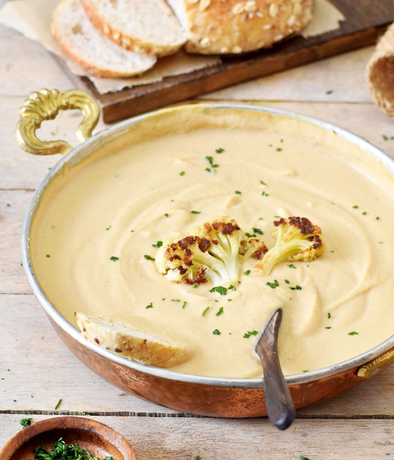 healthy vegan roasted cauliflower soup in bowl with spoon and bread