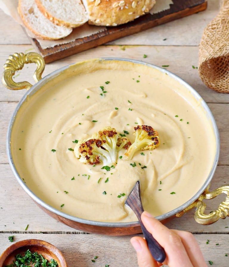 eating roasted cauliflower soup with spoon from bowl