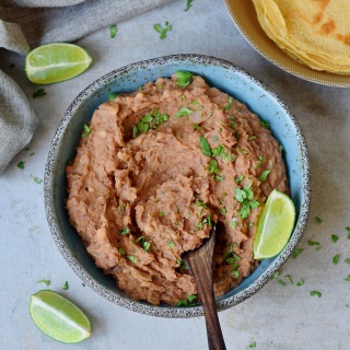 Instant Pot Refried Beans in a blue bowl with tortillas