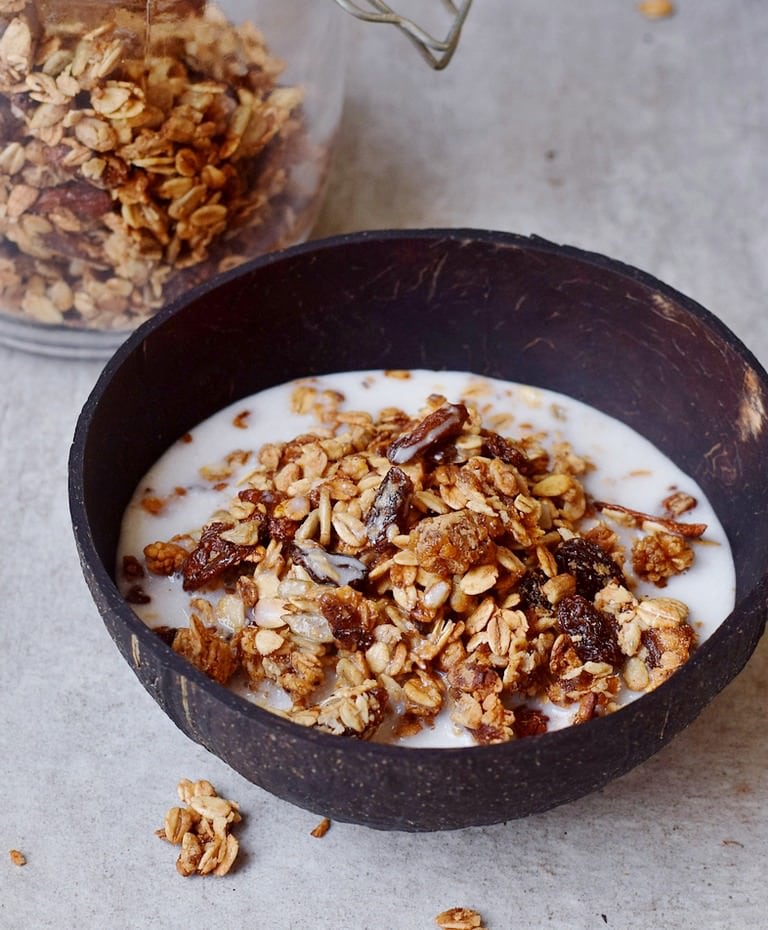 homemade muesli in a coconut bowl with plant-based milk