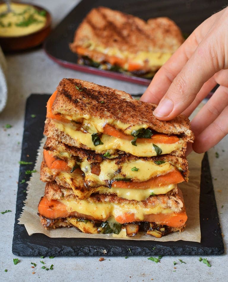 Hand holding vegan grilled cheese sandwiches