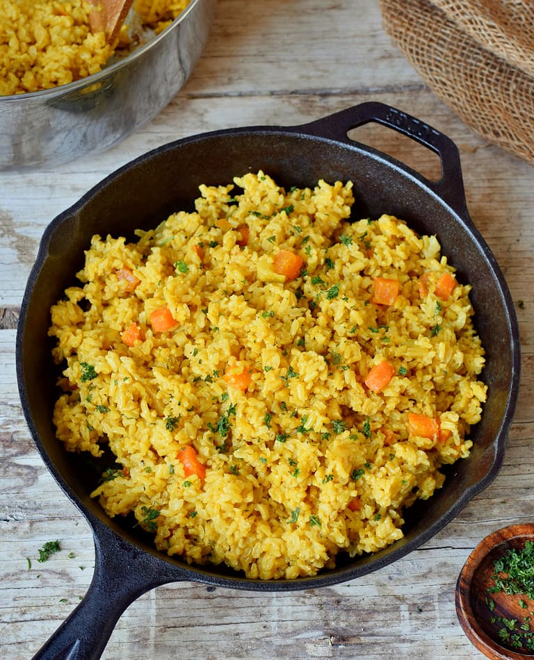 Goldene Reispfanne mit Gemüse und Kokosmilch in einer schwarzen Pfanne