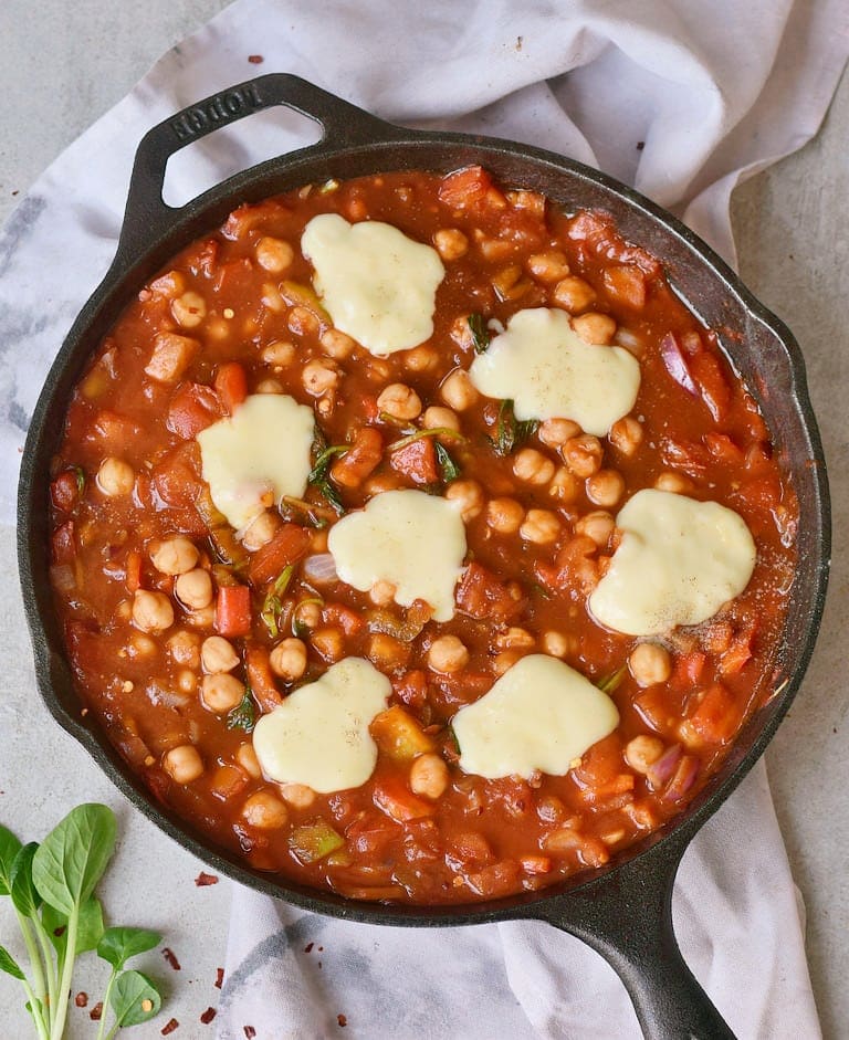 Tomato stew with plant-based cheese in a black pan