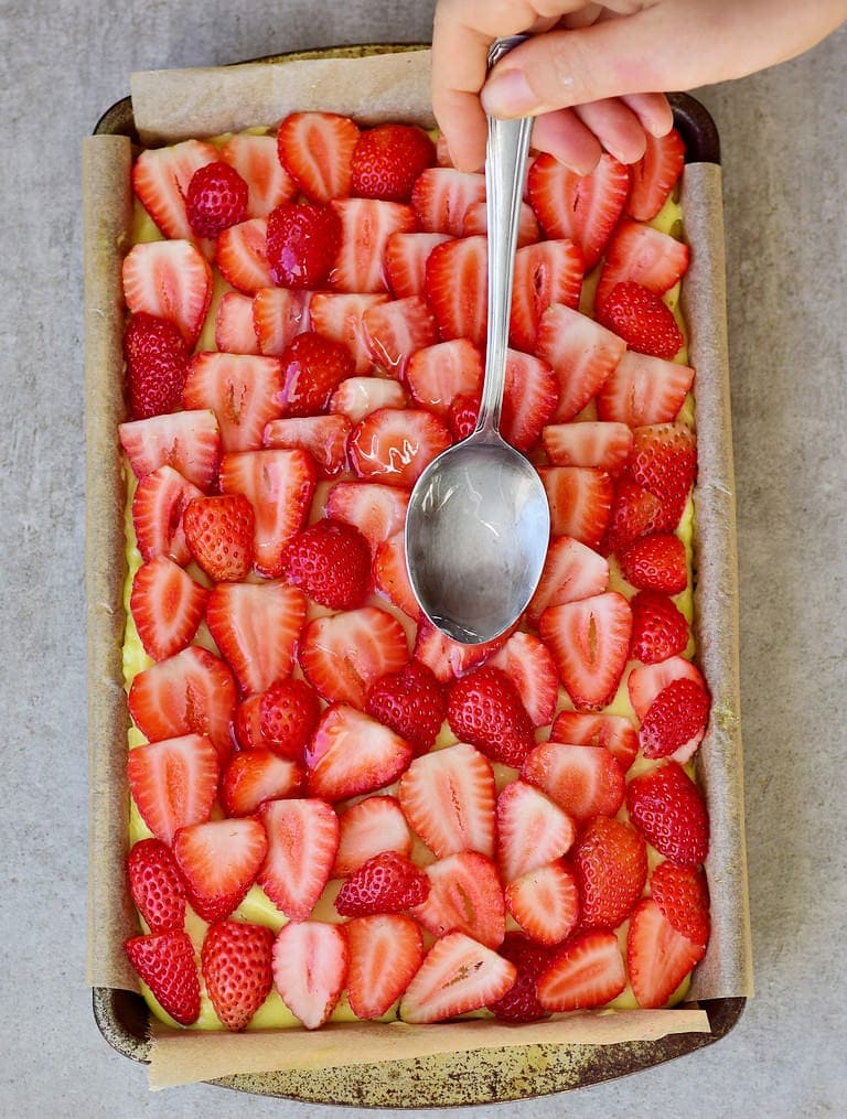 Tortenguss Glasur wird auf einem Erdbeer-Puddingkuchen verteilt