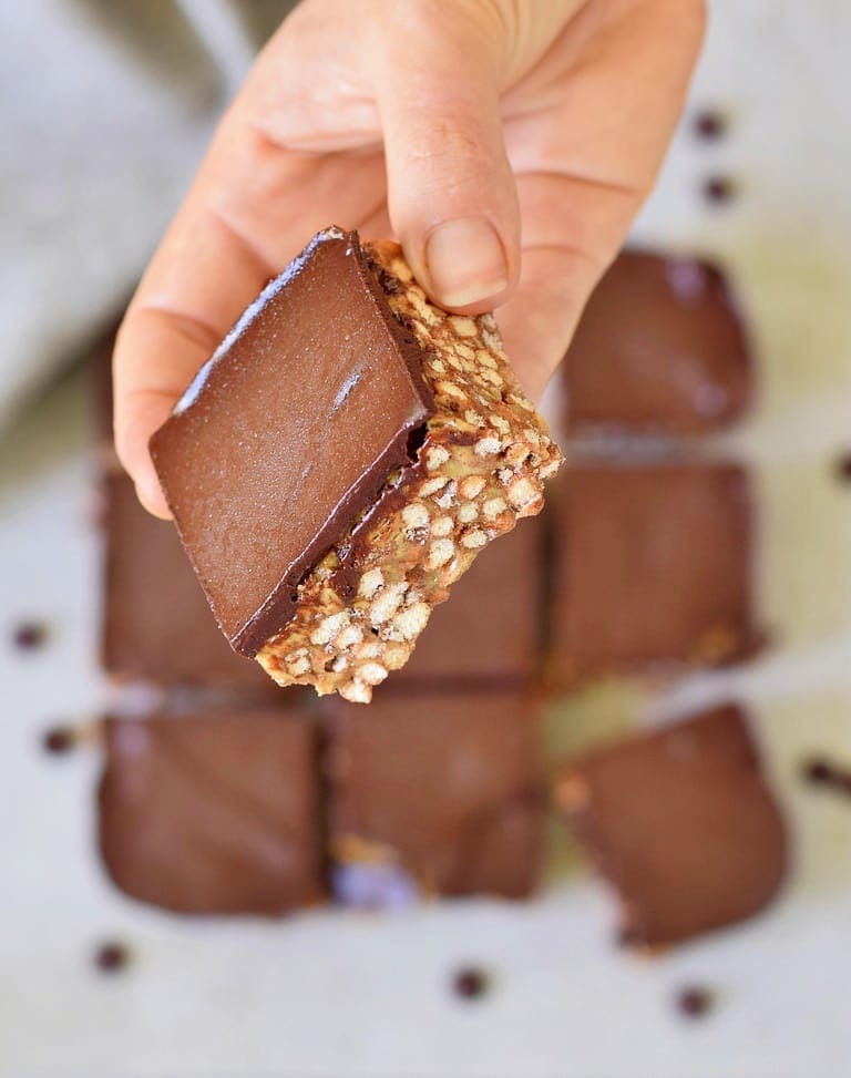 Ein Erdnussbutter-Puffreis-Riegel mit Schokolade wird in einer Hand gehalten