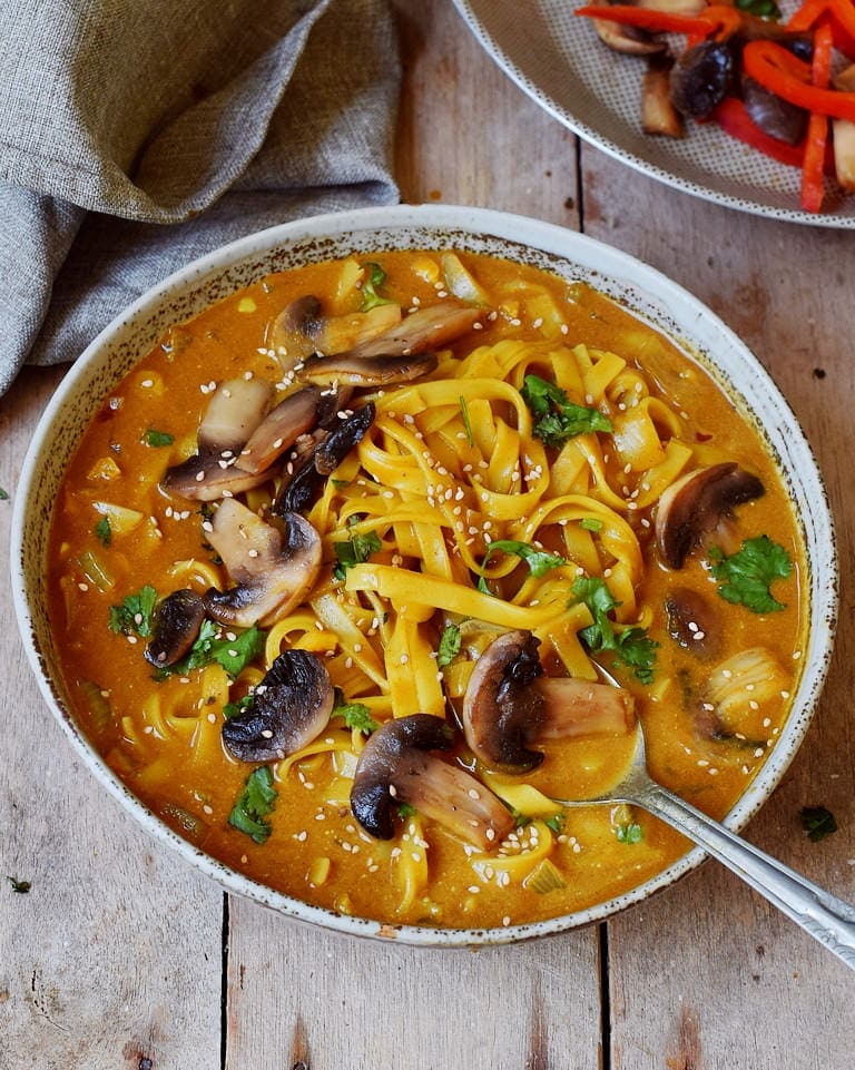 Selbstgemachte scharfe thailändische Suppe mit Champignons und Reisnudeln