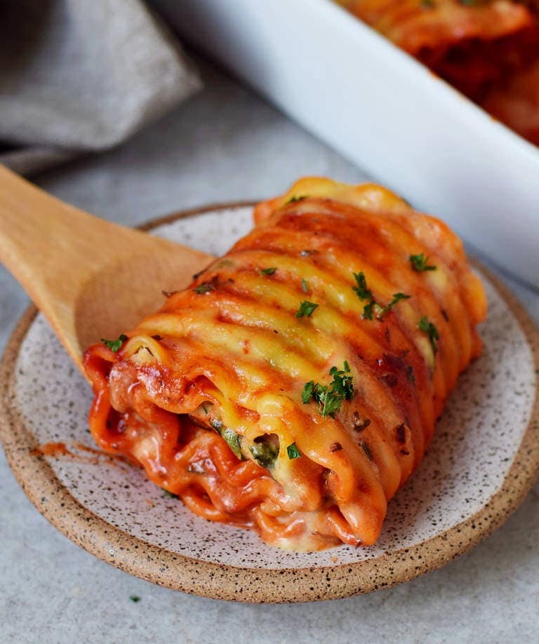 One Lasagna roll on a plate stuffed with hummus
