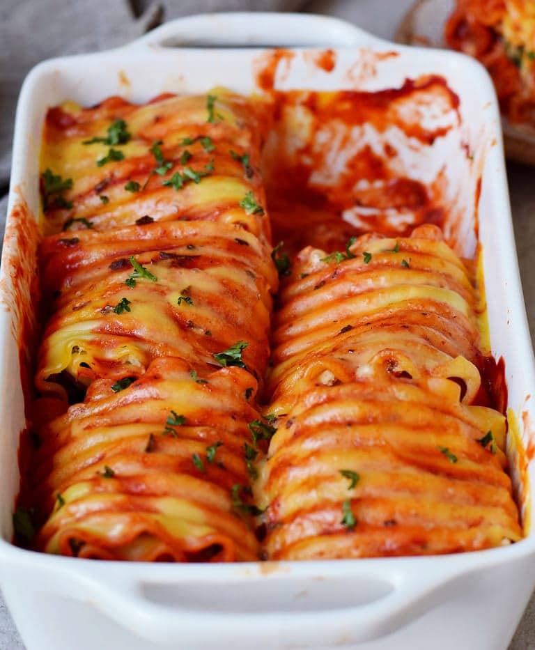 Vegetable Lasagna roll ups in a baking dish with vegan cheese