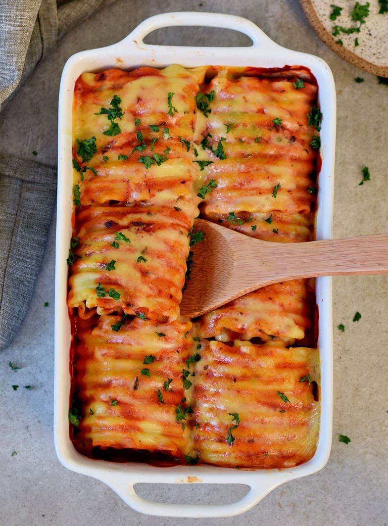 Vegetarian lasagna rolls in a baking dish stuffed with hummus