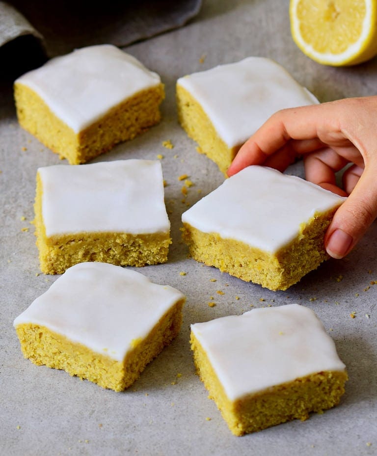 hand grabbing a piece of lemon cake with sugar-free frosting