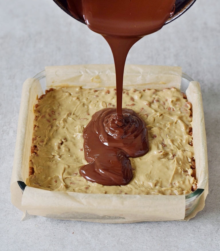 Schokolade wird in eine Form gegossen mit Puffreis und Erdnussbutter