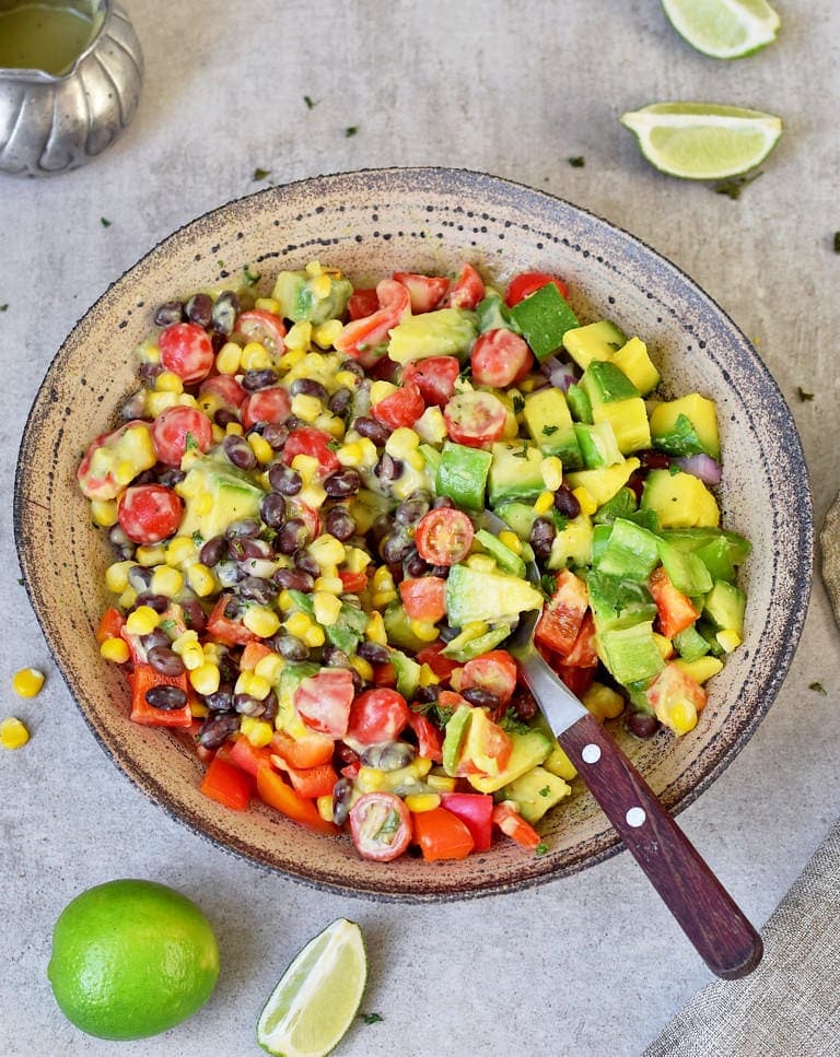Gesunder mexikanischer Avocado Maissalat mit Paprika, Tomaten, schwarzen Bohnen, ölfreiem veganem Dressing