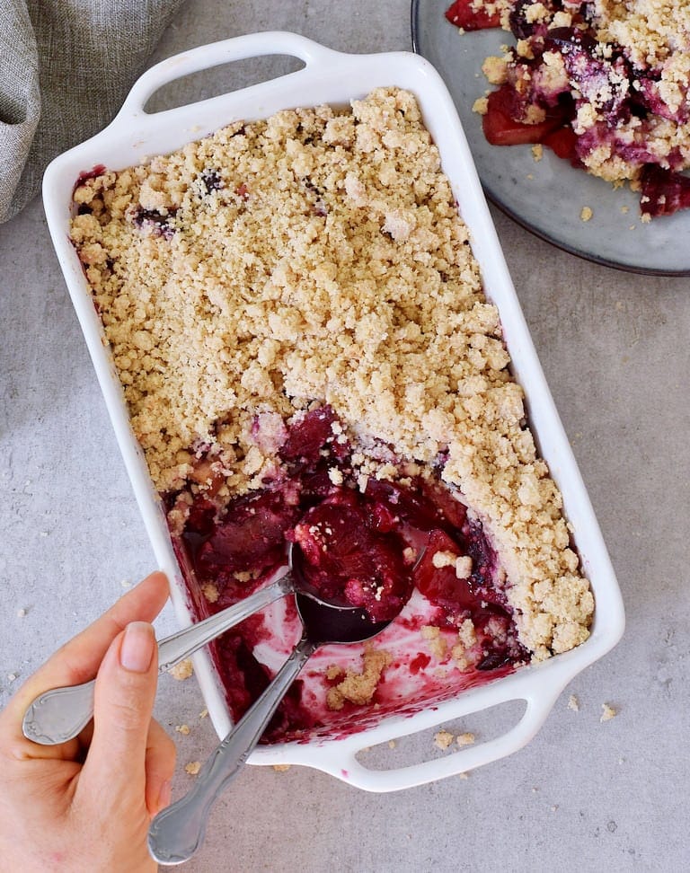 healthy apple crisp with plums in a baking dish