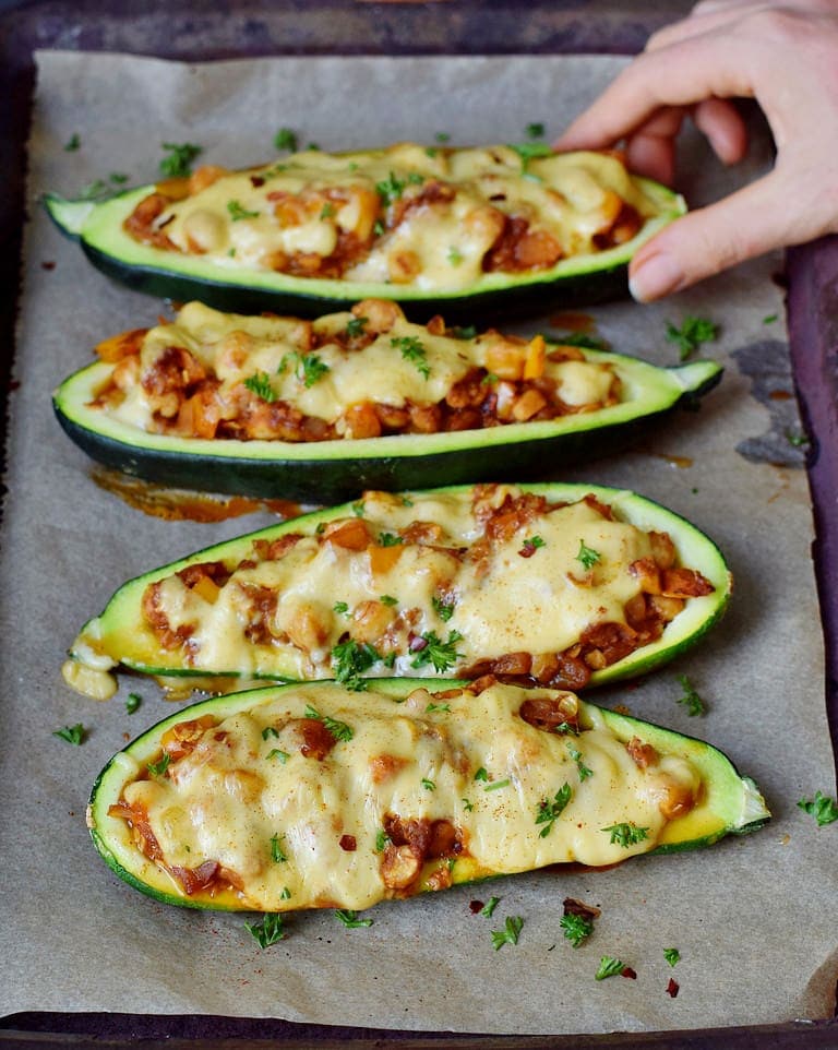 chickpea stuffed zucchini with vegan cheese on a baking sheet