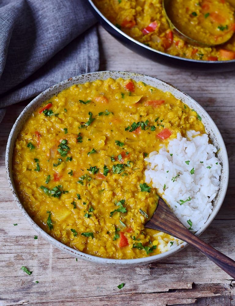 lentil dal with rice in a bowl with wooden spoon