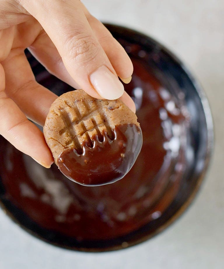 dipping a vegan peanut butter cookie in chocolate