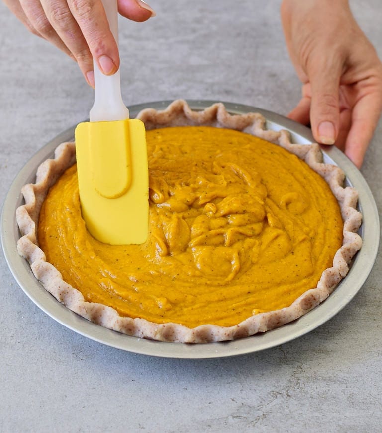 smoothing out pumpkin puree in a pie crust