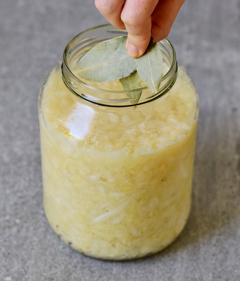 Adding bay leaves to a jar of German sauerkraut