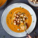 Eating carrot soup with croutons and pumpkin seeds