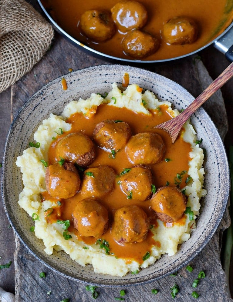 Gluten-free vegan meatballs with gravy over mashed potatoes in a bowl with a spoon