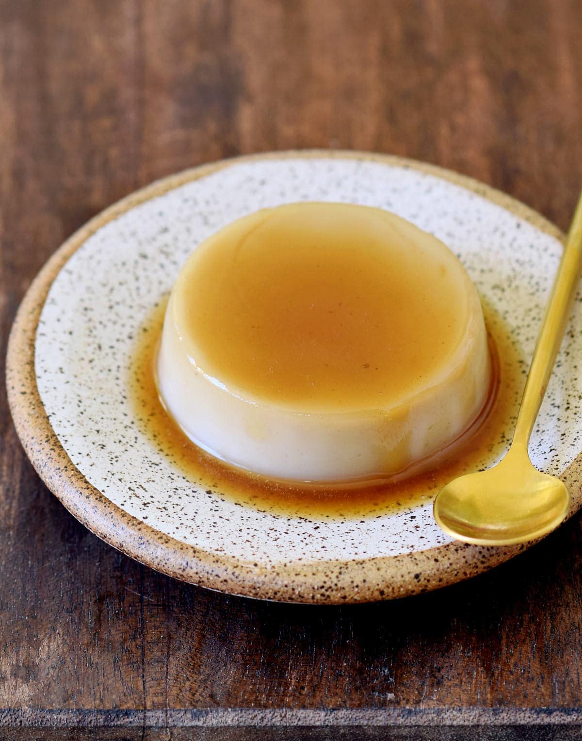 creme caramel with a golden spoon on a plate