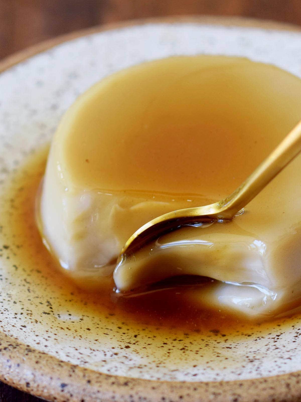 golden spoon submerged in vegan flan