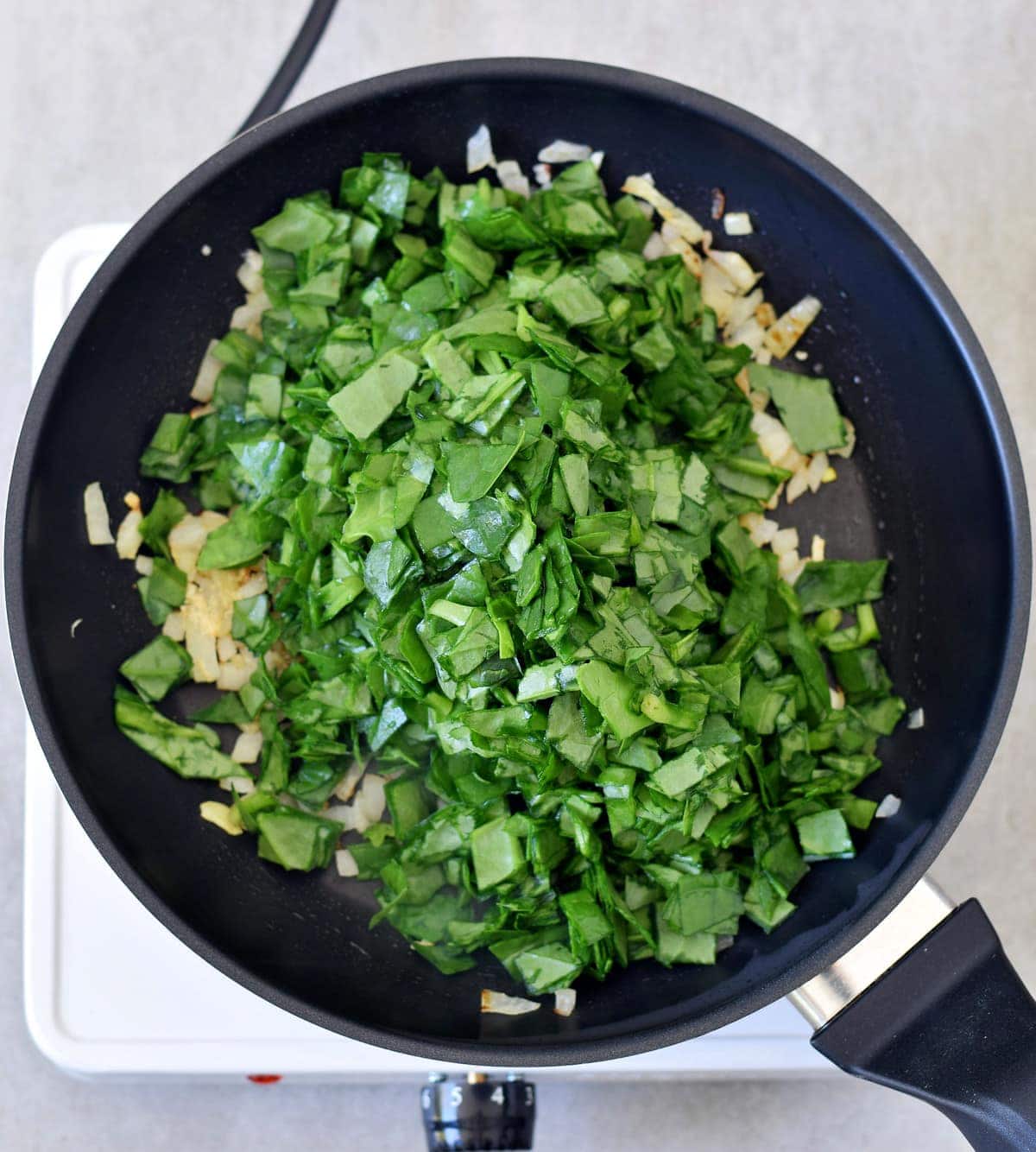 onions and chopped spinach in a pan