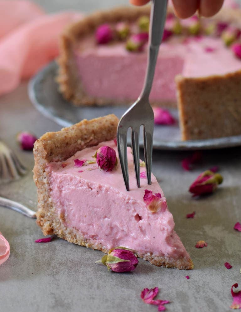 Ein Stück rosaner veganer Käsekuchen mit Kuchengabel
