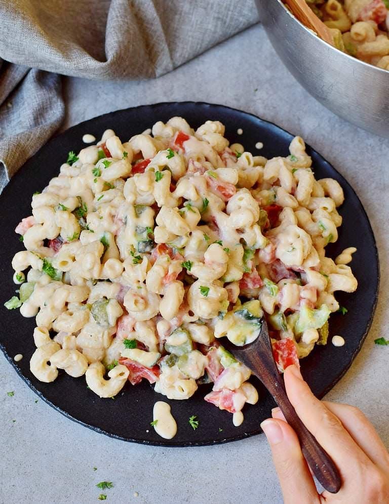 Hand with spoon eating vegan pasta salad