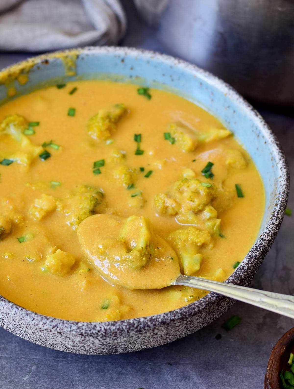 close-up of vegan broccoli cheese soup in a bowl with a spoon