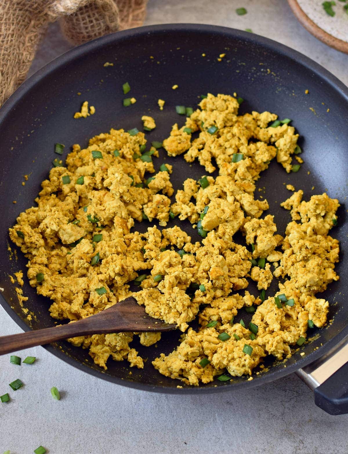 tofu scramble with chives in a black skillet