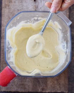 Blended vegan Alfredo sauce in a blender with a spoon