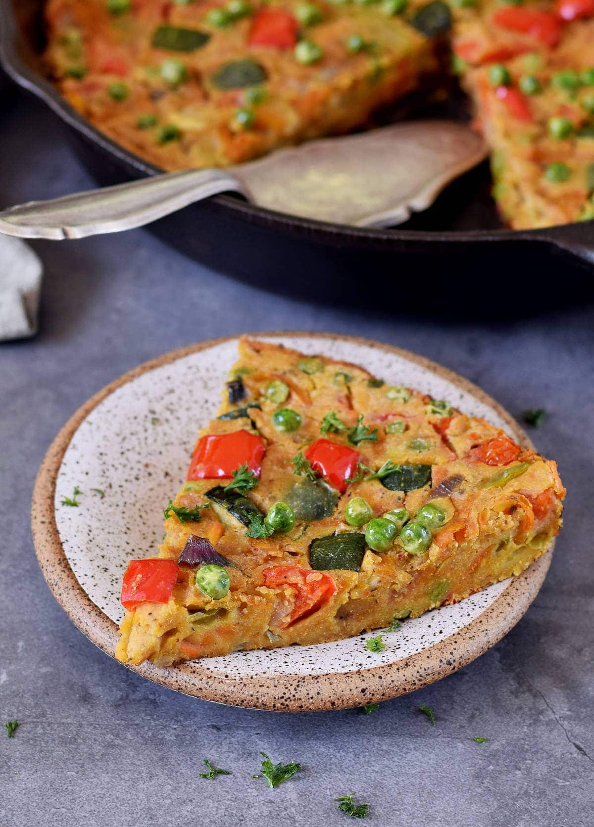 Side view of one piece of vegan veggie frittata on a plate