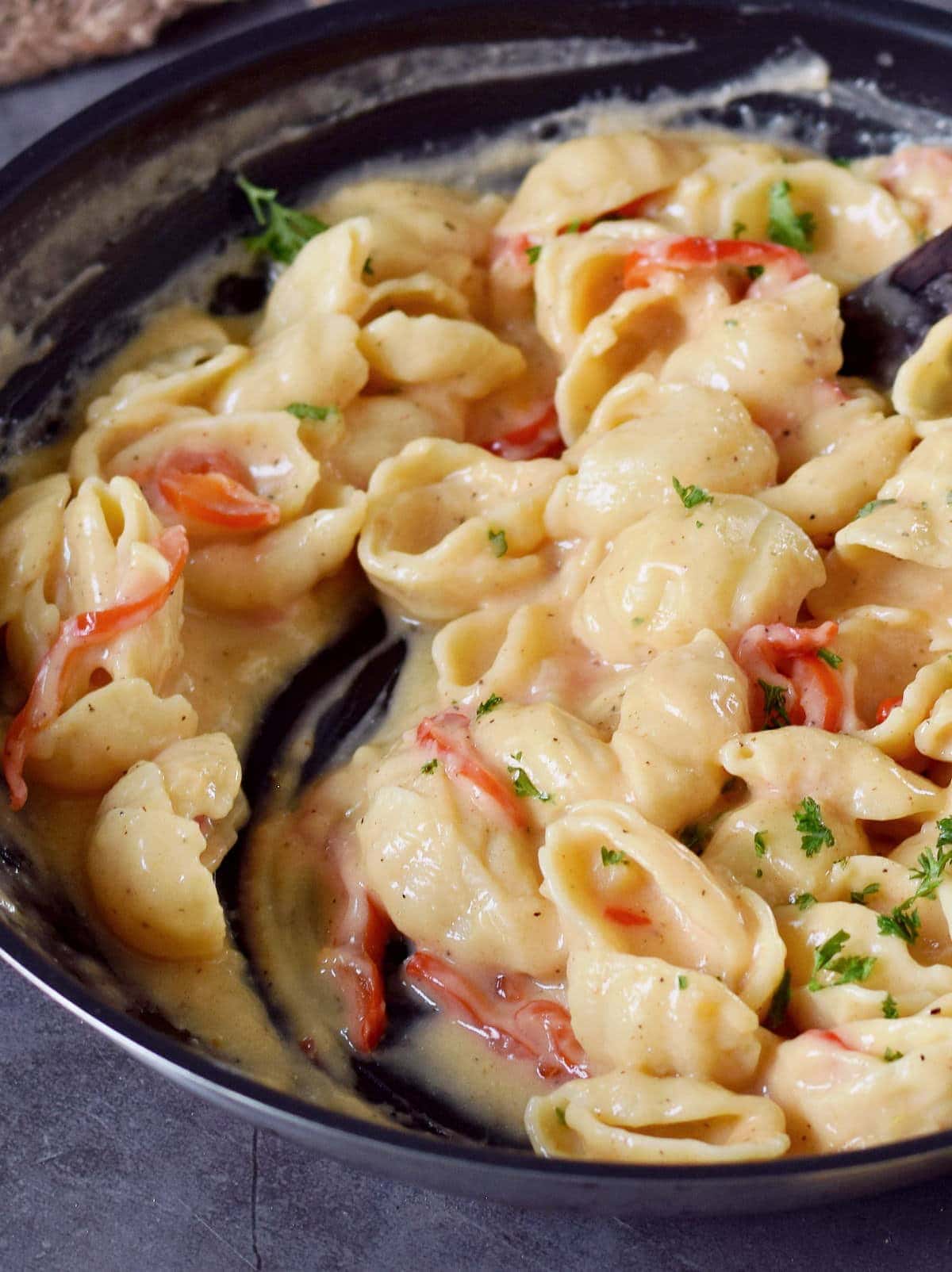 close-up of creamy garlic pasta with red pepper in a skillet
