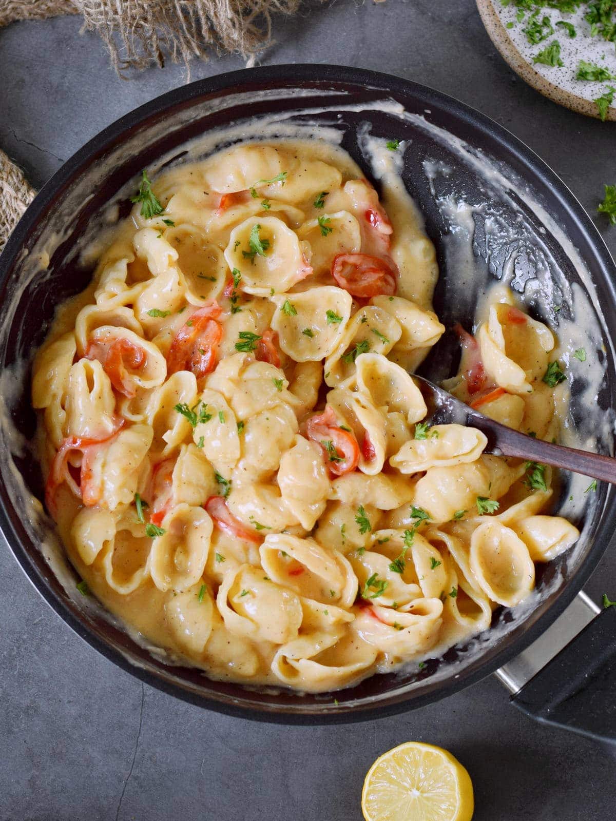 creamy vegan garlic butter pasta with red peppers in a black skillet