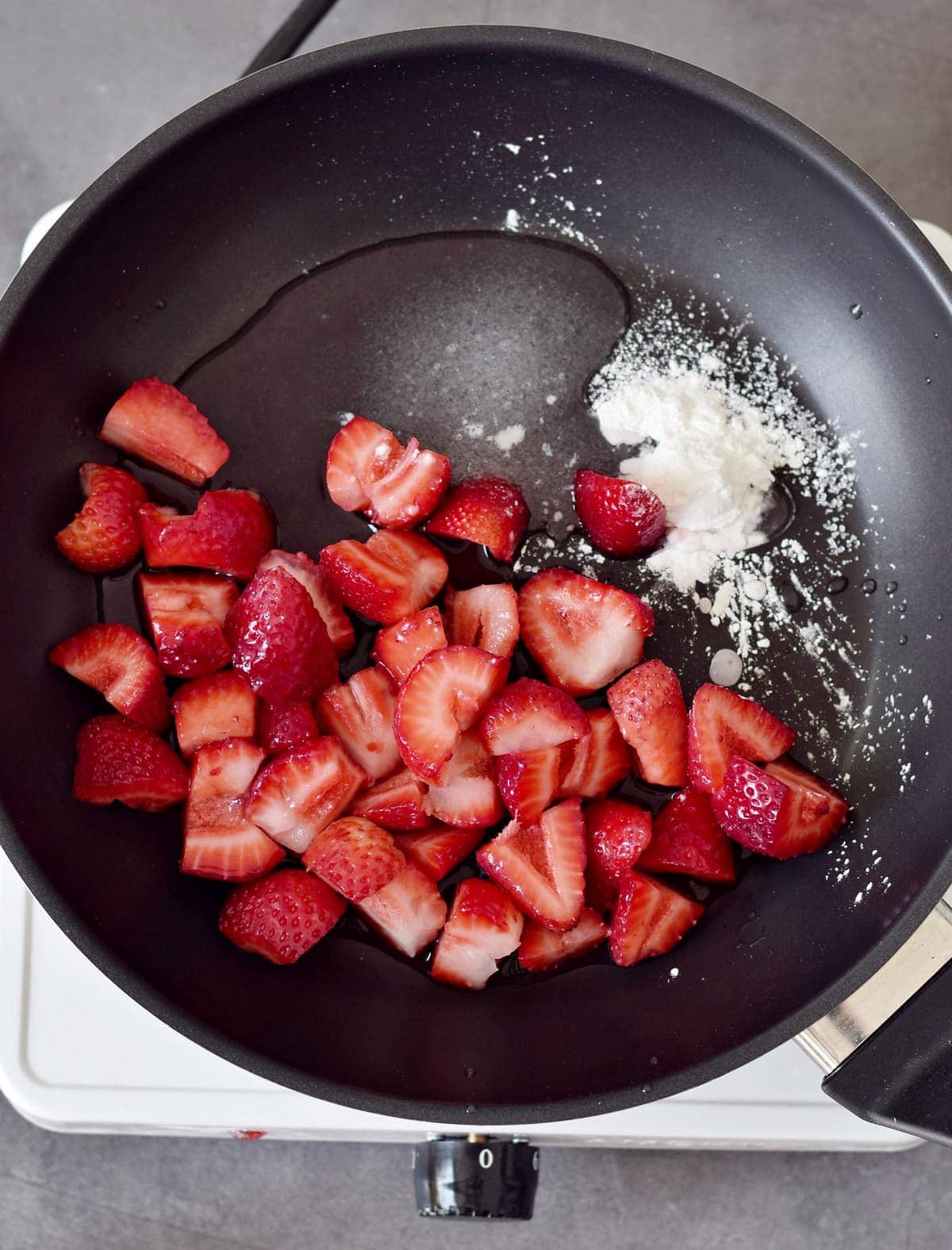 strawberry pieces with cornstarch and water in a black pan