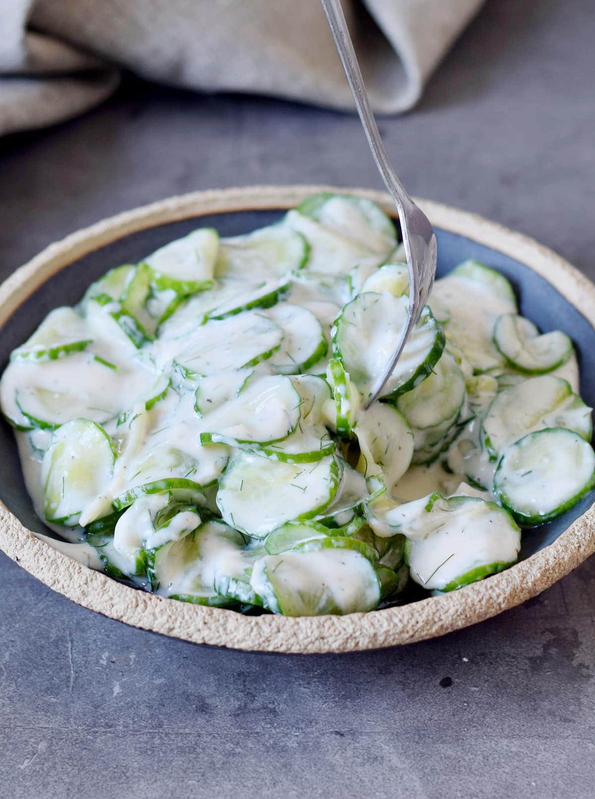 Creamy cucumber salad with vegan dressing on a black plate