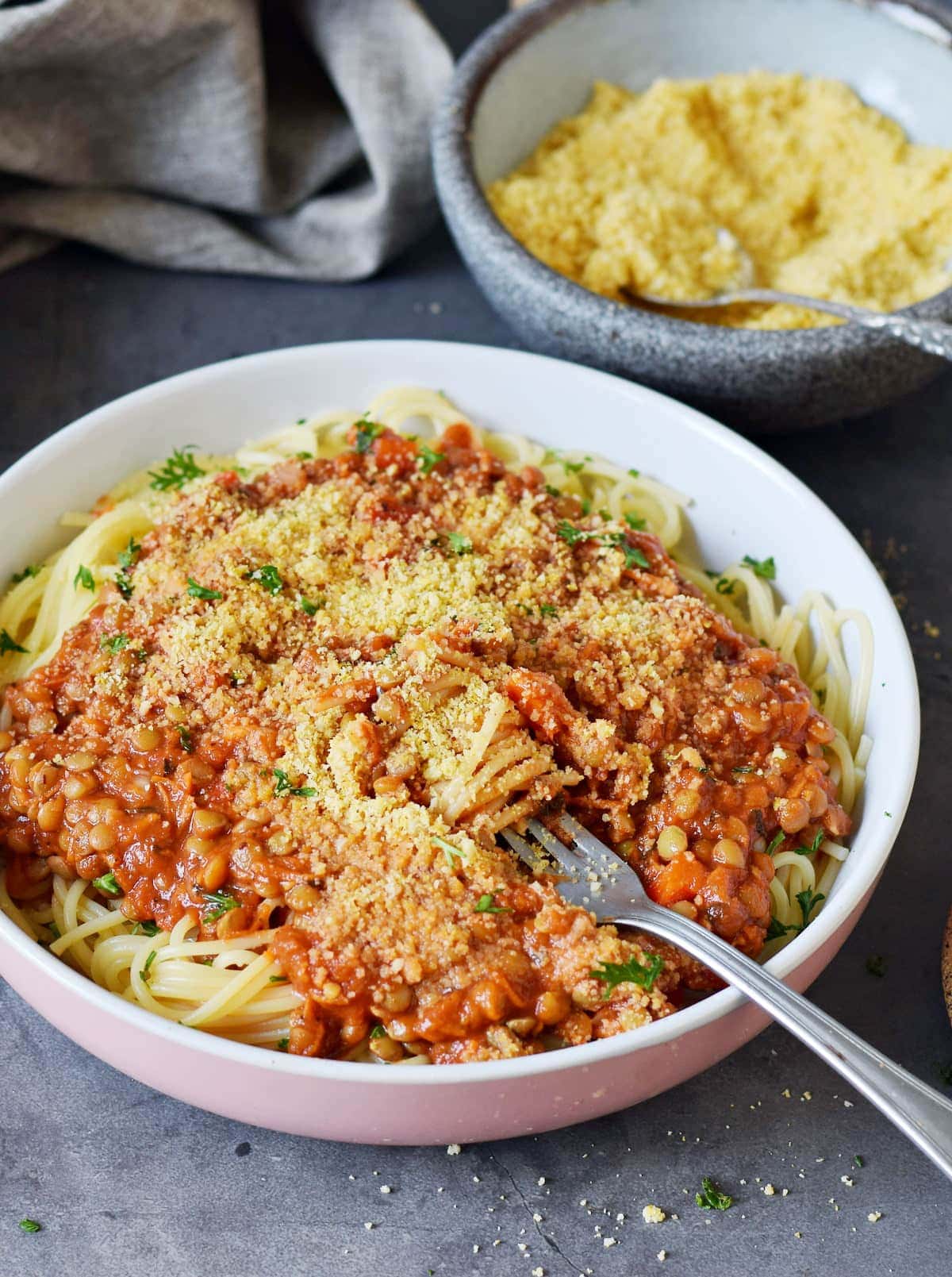 close-up of vegan bolognese with spaghetti in a bowl sprinkled with dairy-free parmesan cheese