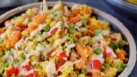 drizzling creamy salad dressing over quinoa pilaf