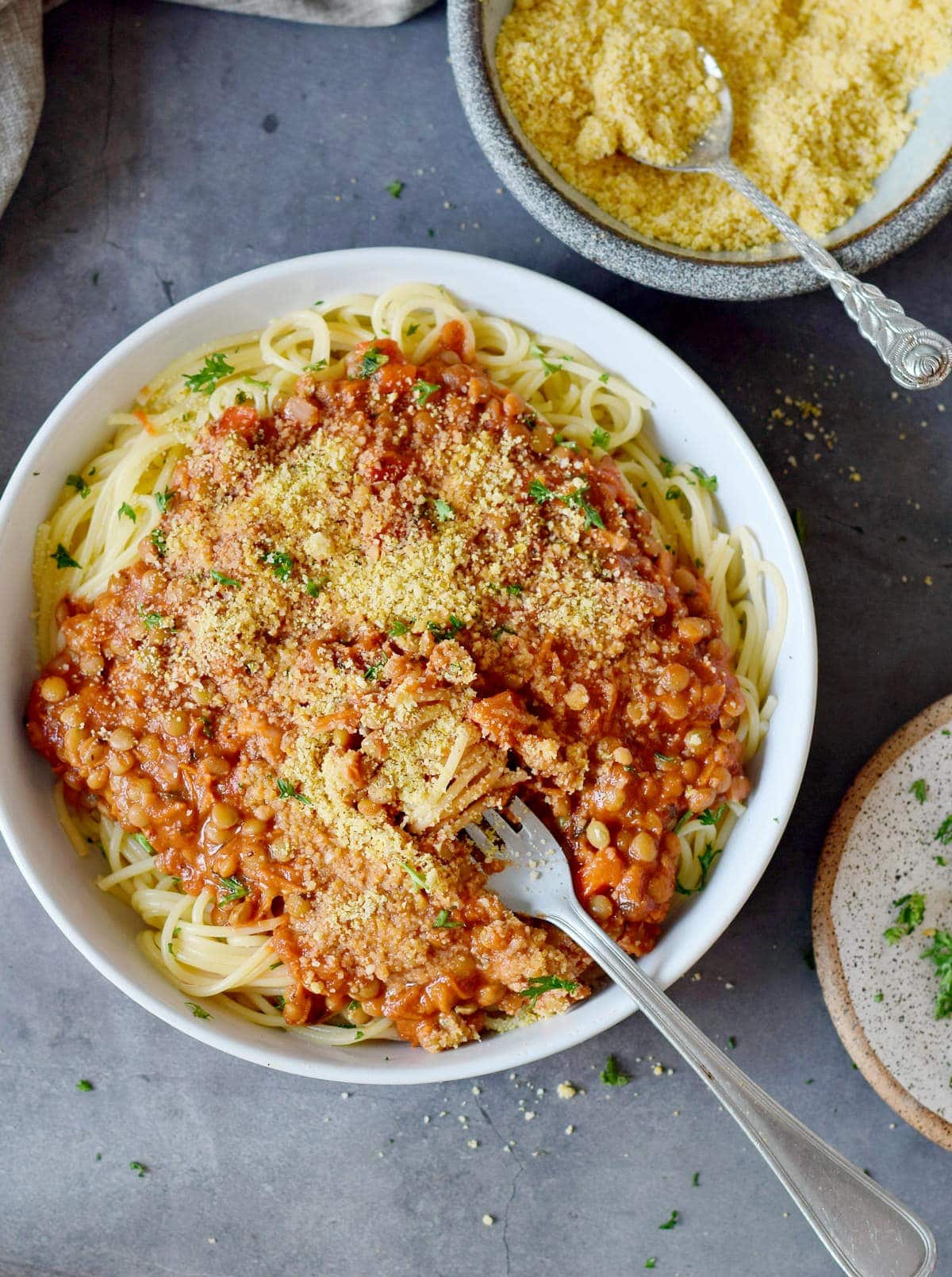 lentil spaghetti bolognese in a bowl sprinkled with vegan parmesan