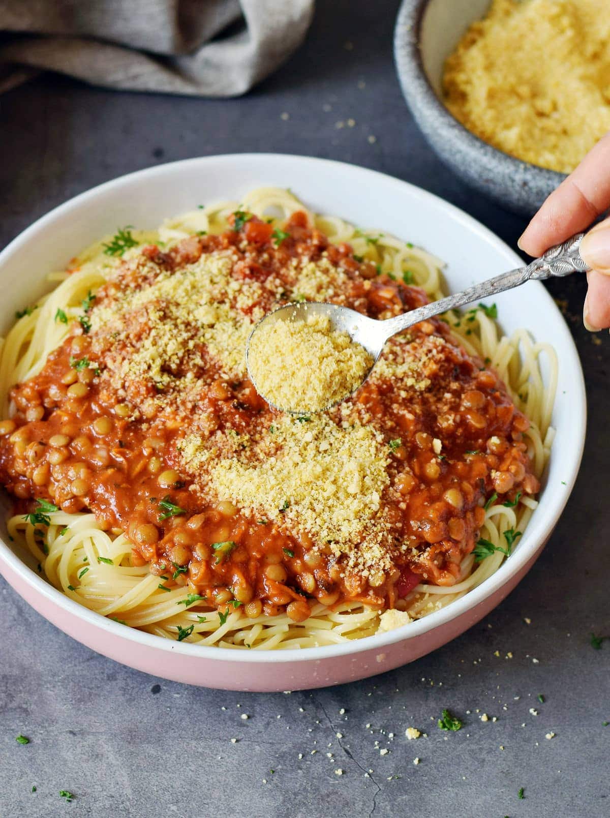 Löffel mit Parmesan Ersatz wird über Spaghetti Bolognese mit Linsen gestreut