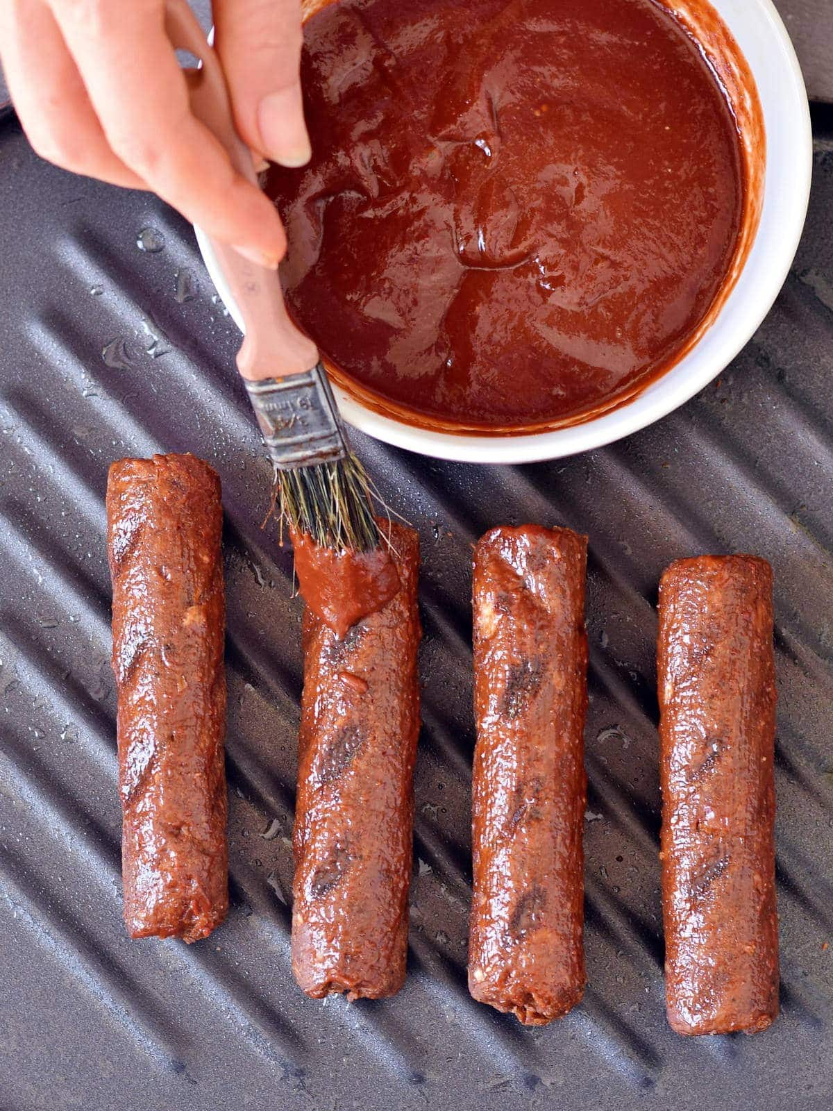 brushing vegan sausages with homemade barbecue marinade