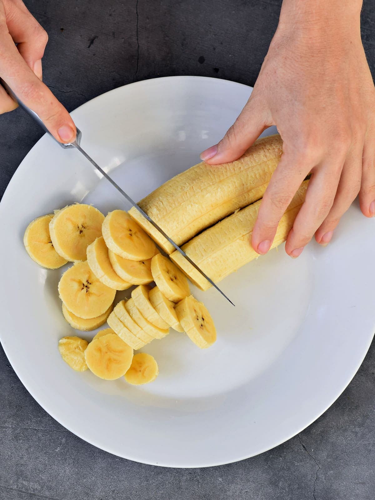 Kochbananen werden mit einem Messer in Scheiben geschnitten