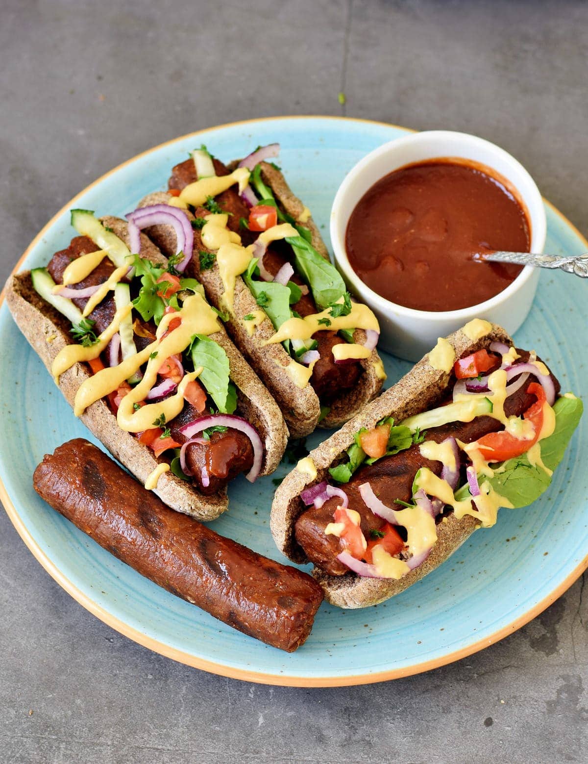 vegan hot dogs with veggies, mustard, and bbq sauce