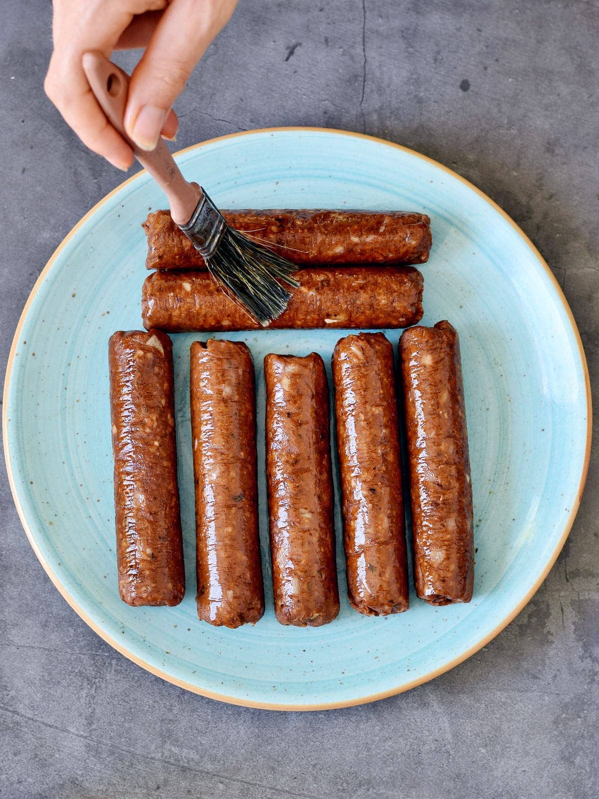 7 vegan sausages on plate brushed with oil