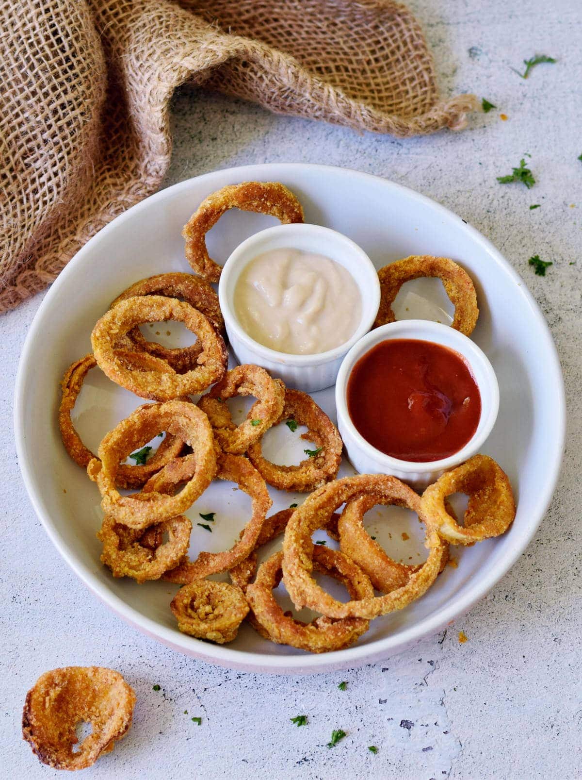 baked chips of onions in bowl with red and white dip