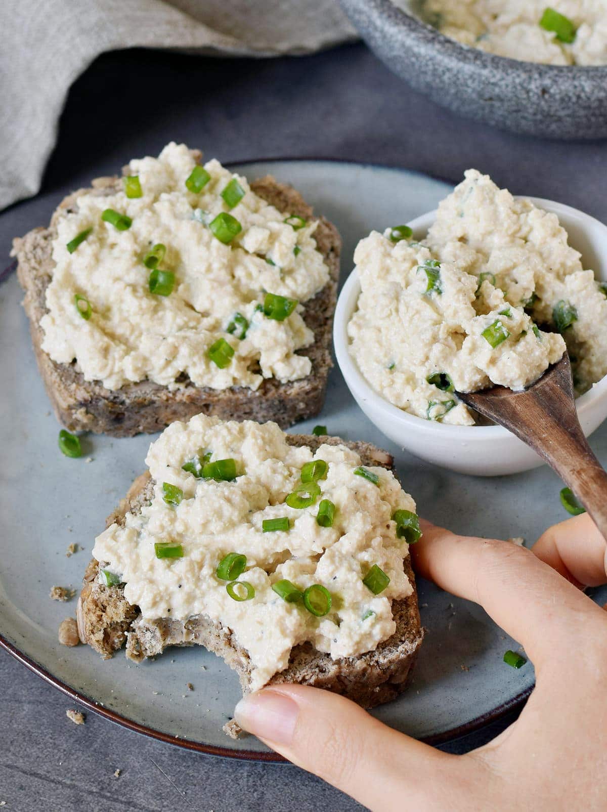 hand grabbing a slice of bread with vegan cottage cheese