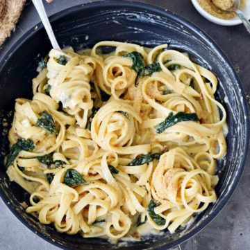 lemon pasta with spinach in black skillet with fork